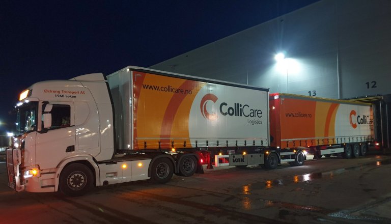A branded ColliCare semi trailer during night, parked to the storage unloading goods