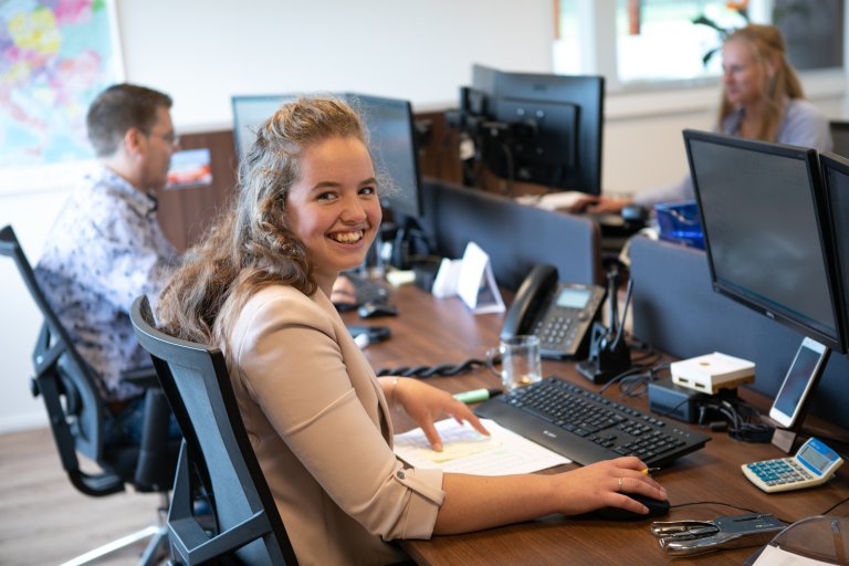 A ColliCare customer service employee smiling behind her computer.